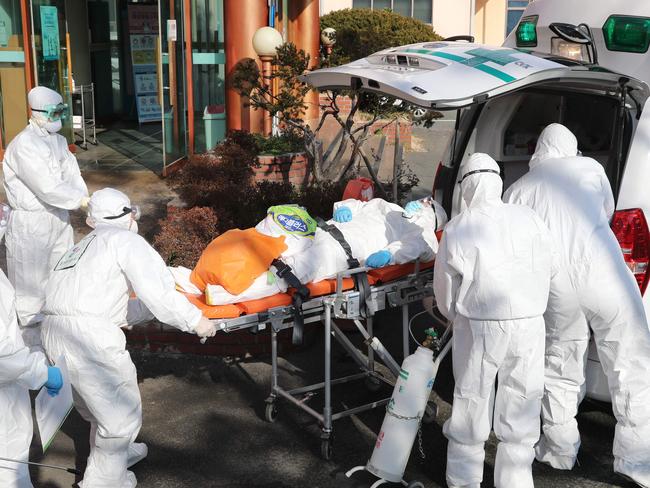 Medical workers wearing protective gear transfer a suspected coronavirus patient to another hospital in South Korea. Picture: YONHAP/AFP