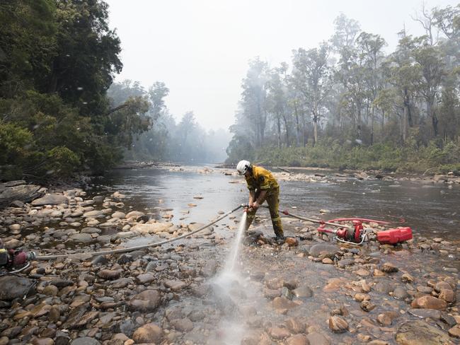 Luke Mellers from the Hobart Fire Brigade RAT Team pumps water out of the Huon River to fight a fire spreading into the Huon Pine Walk. in the Tahune area. Picture: WARREN FREY/TFS