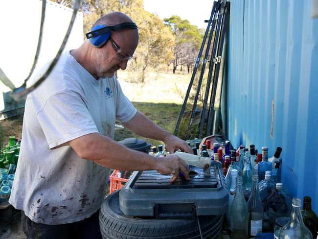 Mark cuts the tops of the beer bottles for his feature wall. Picture: Toby Zerna