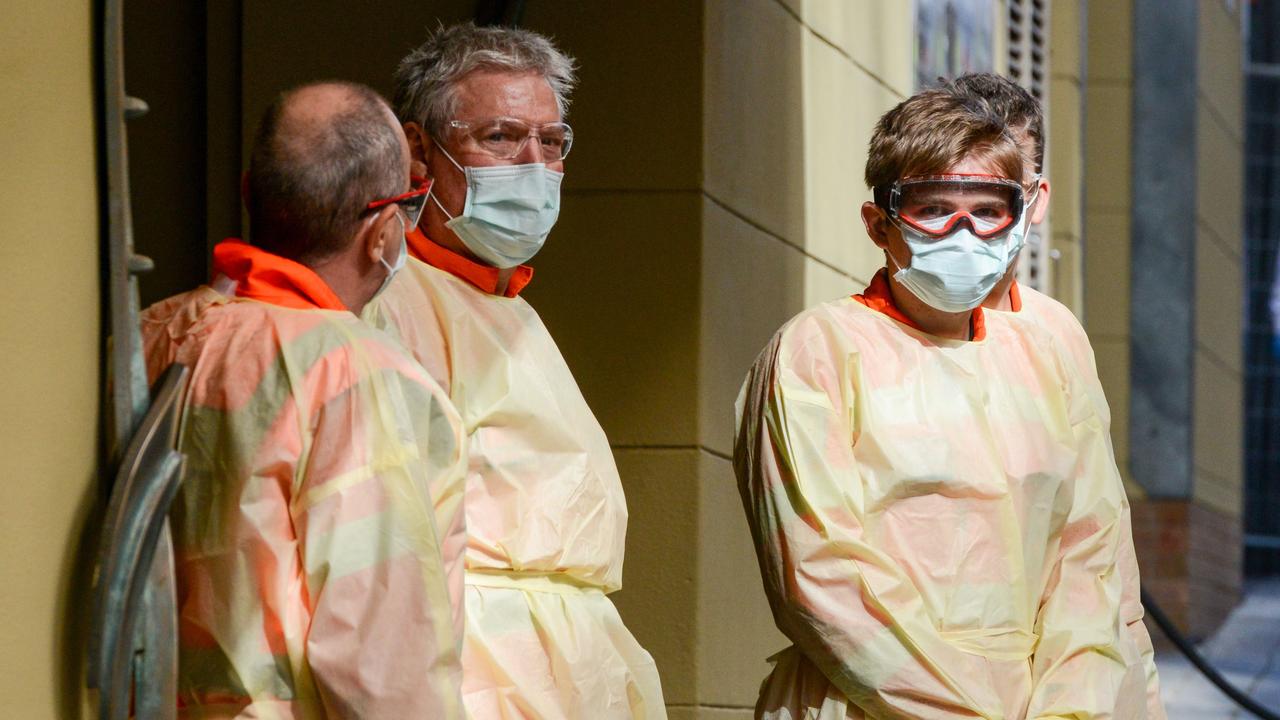 Local officials in protective gear wait at a hotel in Adelaide earlier this year for the arrival of Australian residents who will go through a mandatory 14-day quarantine. Picture: Brenton Edwards/AFP