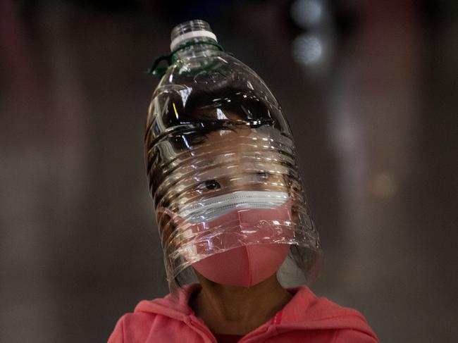 BEIJING, CHINA - JANUARY 30: A Chinese girl wears a plastic bottle as makeshift homemade protection and a protective mask while waiting to check in to a flight at Beijing Capital Airport on January 30, 2020 in Beijing, China. The number of cases of a deadly new coronavirus rose to over 7000 in mainland China Thursday as the country continued to lock down the city of Wuhan in an effort to contain the spread of the pneumonia-like disease which medicals experts have confirmed can be passed from human to human. In an unprecedented move, Chinese authorities put travel restrictions on the city which is the epicentre of the virus and neighbouring municipalities affecting tens of millions of people. The number of those who have died from the virus in China climbed to over 170 on Thursday, mostly in Hubei province, and cases have been reported in other countries including the United States, Canada, Australia, Japan, South Korea, and France. The World Health Organization  has warned all governments to be on alert, and its emergency committee is to meet later on Thursday to decide whether to declare a global health emergency. (Photo by Kevin Frayer/Getty Images)