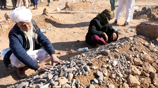 Afghan mourners sit beside a grave after funeral prayers for their relative's body from the earthquakes in Sarbuland village, Zendeh Jan district of Herat province on Sunday. Picture: AFP