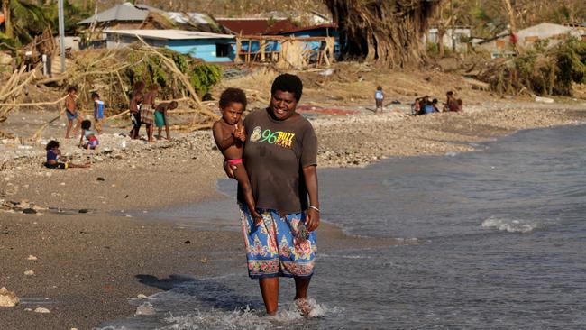 Katheen Nawioe, with her daughter Windy, on the beach at Lenakel yesterday as islanders continue the clean up. Picture: Stuart McEvoy