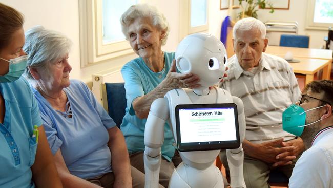 Scientist Sebastian Hofstetter (right) from the Medical Faculty of the Martin Luther University Halle-Wittenberg, Germany, presents the robot “Thea”, programmed with various pieces of music, to the residents of an aged care home. The aim is to sensitise and train nursing staff in the field of digitalisation. But a robotic nurse is “just fairyland stuff”. Picture: Waltraud Grubitzsch/picture alliance via Getty Images