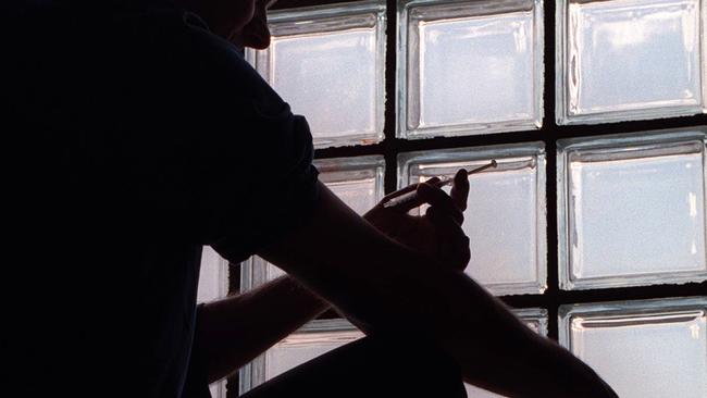 A drug addict shoots up heroin with a syringe in Cabramatta in July 1997.