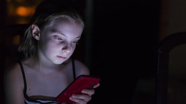 Teenager checks her mobile phone in bed during the night. technology, internet, communication and people concept - close up of teen girl texting on smartphone at home at night.  Internet Addiction Disorder