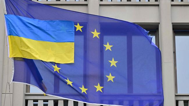 A smaller Ukrainian flag flies next to a flag of the European Union. (Photo by John MACDOUGALL / AFP)