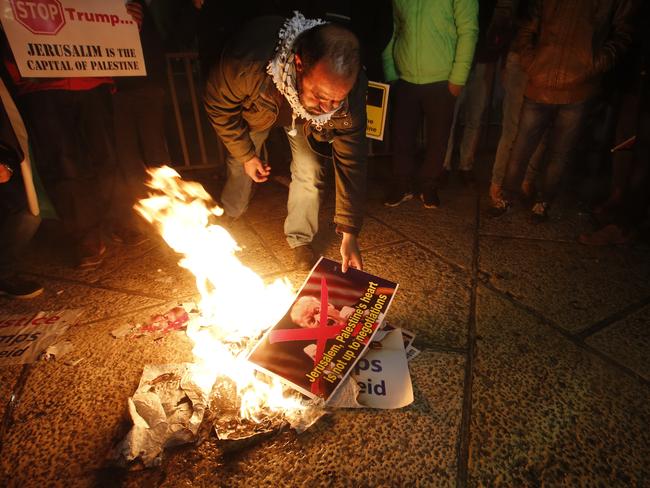 A Palestinian burns a poster of President Trump during a protest in Bethlehem, West Bank. Picture: AP