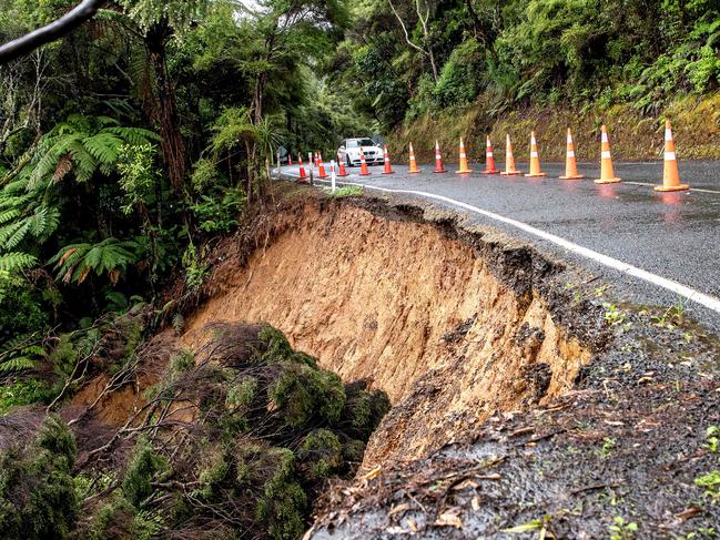 A car makes its way on a road damaged by a flash flood after heavy rain on the outskirts of Auckland. Picture: AFP