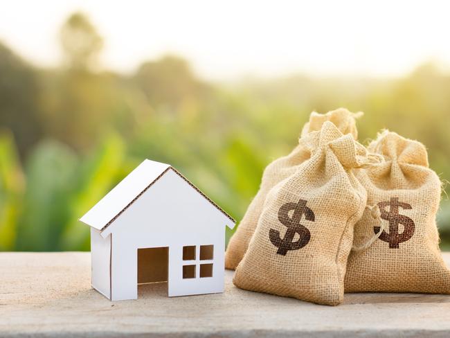 Loan and House concept. Money bags put near house on woodle desk at sunset and green nature background