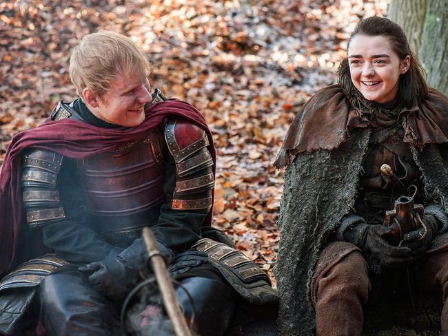 This image released by HBO shows Ed Sheeran, left, and Maisie Williams in a scene from "Game of Thrones." Sheeran appeared as a Lannister soldier leading a group in song in the season premiere of the hit HBO fantasy drama, which debuted on the premium cable channel Sunday night. (Helen Sloan/HBO via AP)