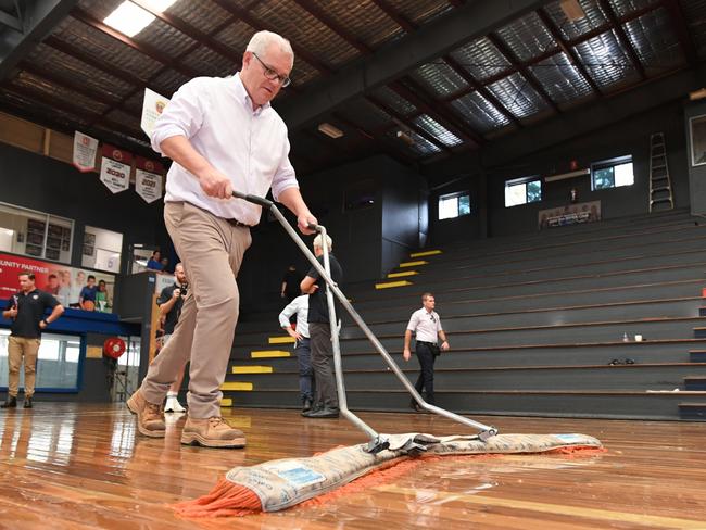 Prime Minister Scott Morrison is seen helping to dry the flood damaged court at the Brisbane Basketball Court in the suburb of Auchenflower in Brisbane, Thursday, March 10, 2022. Prime Minister Morrison will make a formal request for a national emergency with the Queensland Premier after devastating floods ravaged southeastern parts of the state. (AAP Image/Darren England) NO ARCHIVING