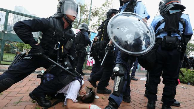 Police officers in anti-riot gear holds down an anti-extradition bill protester. Picture: SCMP / Felix Wong