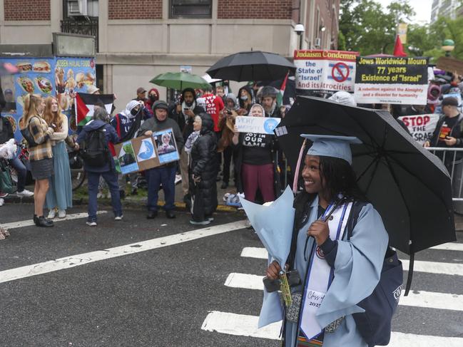 A graduate poses for a photo in front of a group of people protesting in support of Palestinians across the street from the main gates of Columbia University this week. Picture: AP