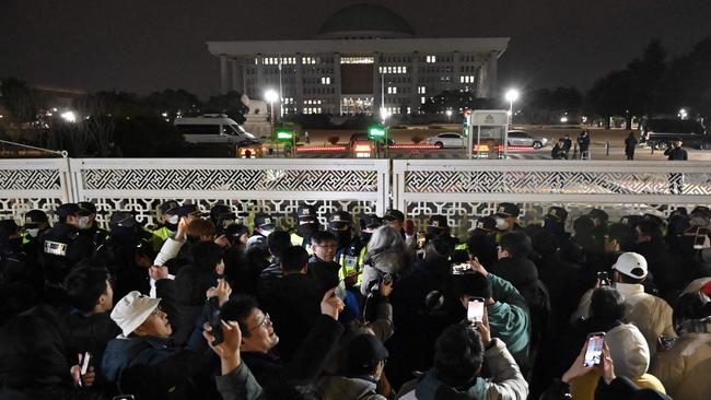 People gather in front of the main gate of the National Assembly in Seoul, South Korea after President Yoon Suk Yeol declared emergency martial law.