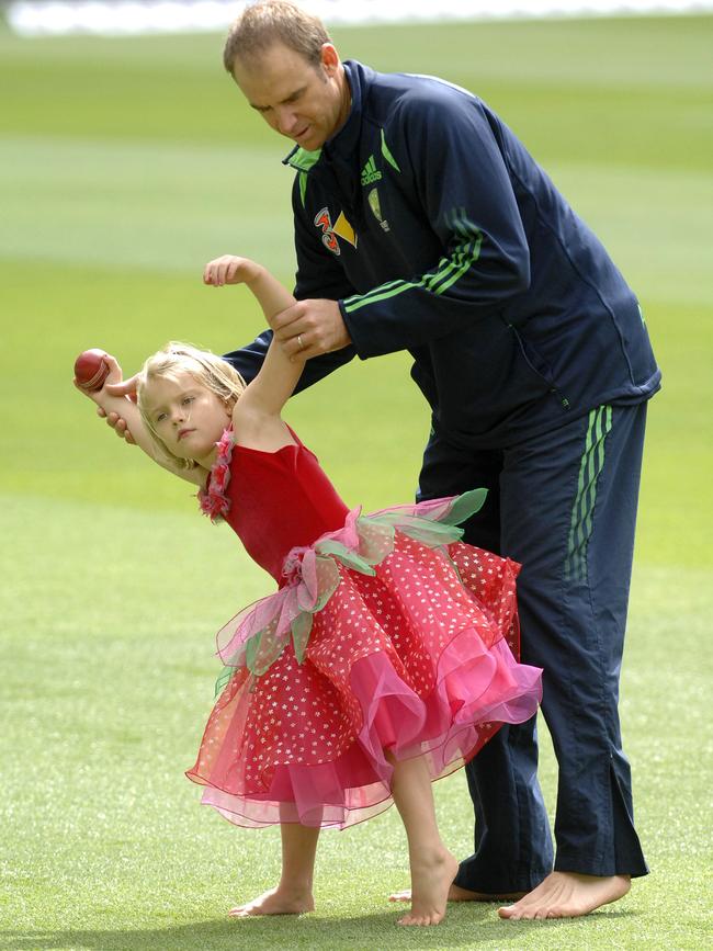 Five-year-old Grace getting some tips from her dad on how to throw a cricket ball.