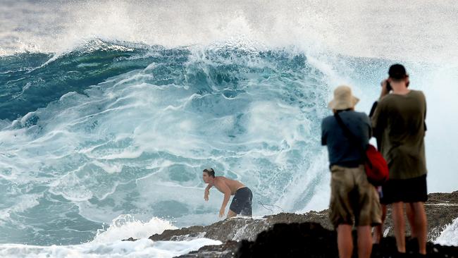 Photographers take photographs of a surfer at Snapper Rocks on the Gold Coast, Thursday February 21, 2019. Huge swells and high tides are set to pummelling southeast Queensland beaches over the coming days as Cyclone Oma tracks towards the Queensland coast. (AAP Image/Dave Hunt)