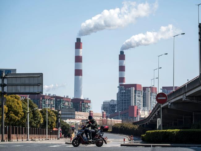 A man rides a scooter near the Shanghai Waigaoqiao Power Generator Company coal power plant in Shanghai. Picture: AFP