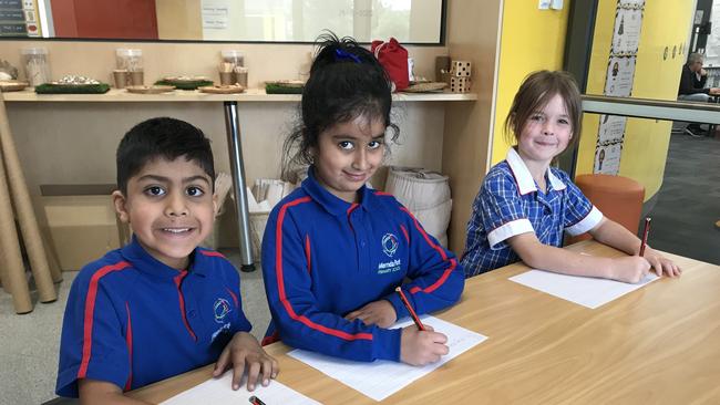 Mernda Park Primary students Kevin, Siya and Harper write their letters to elderly residents.