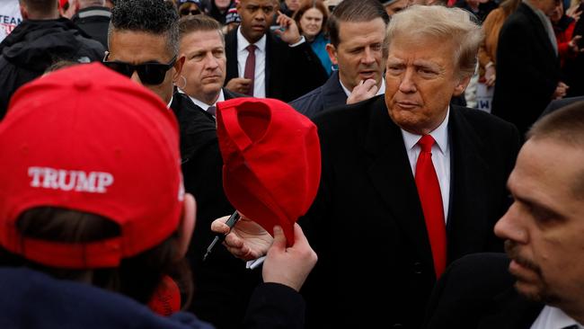 Republican presidential candidate Donald Trump autographs hats while visiting with supporters outside the polling site at Londonderry High School on January 23. Picture: Chip Somodevilla / GETTY IMAGES NORTH AMERICA / Getty Images via AFP