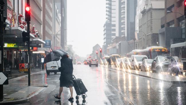 A woman walks across Grenfell Street at the James Place crossing in the rain. Picture: AAP / Morgan Sette