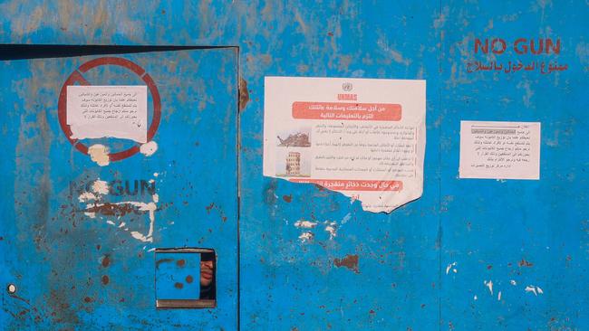 A man peeks out of an opening in the gate of an UNRWA aid distribution centre in the Nuseirat refugee camp in the central Gaza Strip. Picture: AFP