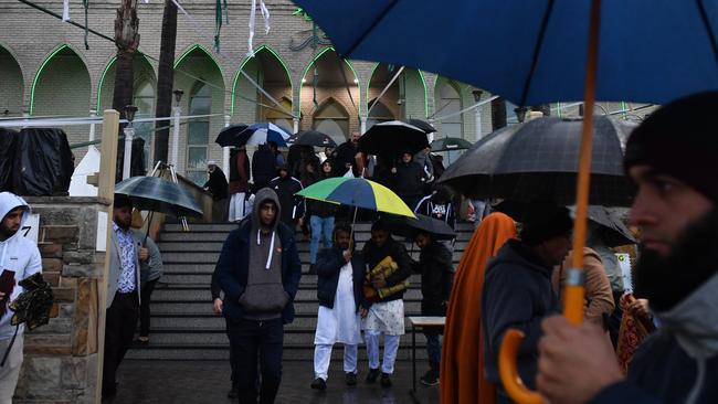 Muslims huddle under umbrellas outside the Lakemba Mosque following Eid prayers. Picture: AAP