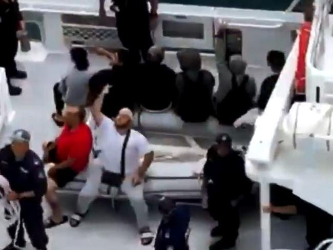 Man on police boat gestures as passengers hurl insults at evicted family. Picture: Nine news.