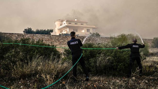 Police fight a raging fire in Lagonisi, 35km outside Athens, on Monday. Picture: AFP