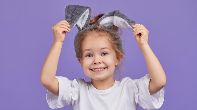 Portrait of cute smiling little child girl wears bunny ears on Easter day. Funny emotions on Violet isolated background