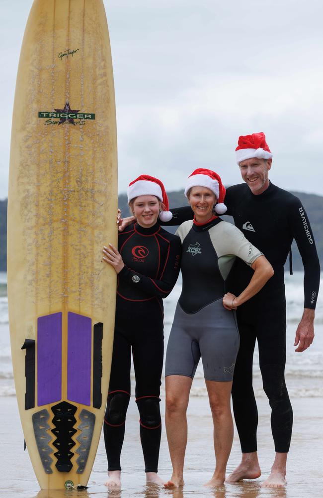 Mike Bishop and Cate Sheahan with their daughter Sally, 13 heading out for a surf at Umina. Picture David Swift.