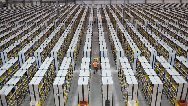 Employees push carts along aisles as they process customer orders ahead of shipping at one of Amazon.com Inc.'s fulfillment centers. It’s an open question whether the Amazon model for apparel retailing can travel. (Simon Dawson/Bloomberg)