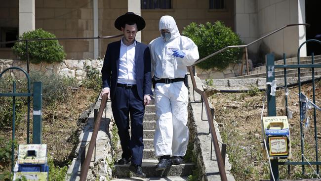 An Israeli police officer wearing protective gear detains a member of the ultra-community after he prayed in a Tel Aviv synagogue in defiance of government measures to help stop the spread of the coronavirus. Picture: AFP