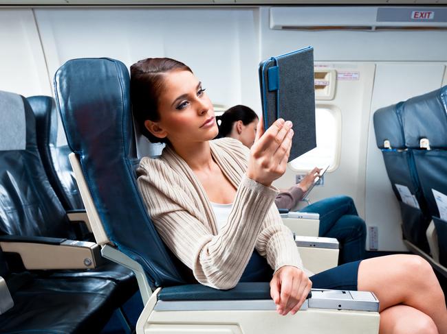 Young woman sitting on the airplane using a tablet.