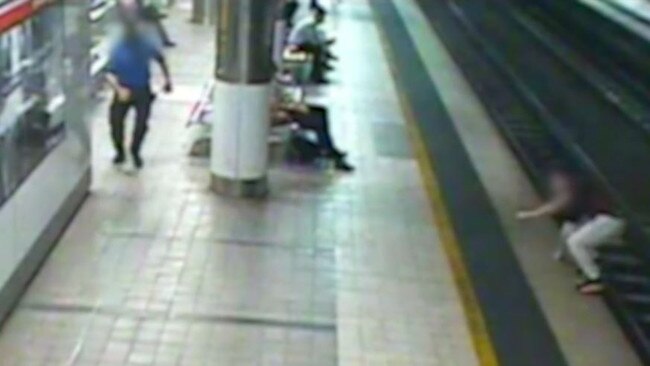 The man climbs onto the platform after crossing over the tracks at Fortitude Valley station.