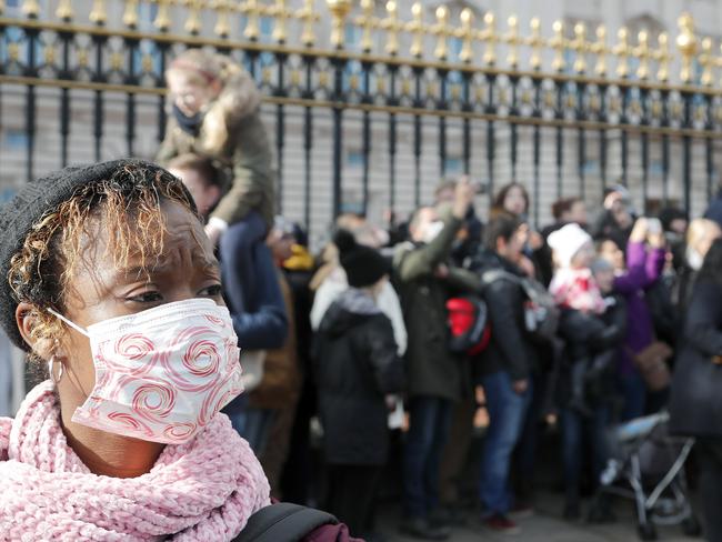 A tourist wears a face mask as she watches the Changing of the Guard, at Buckingham Palace. Picture: AP