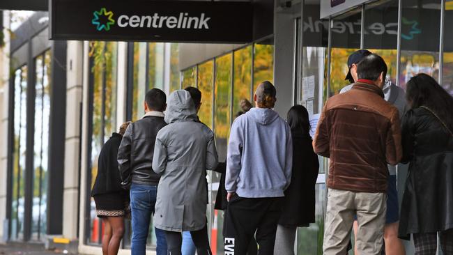 People queue up outside a Centrelink office in Melbourne on April 20, 2020, which delivers a range of government payments and services for retirees, the unemployed, families, carers and parents amongst others. - A report from the Grattan Institute predicts between 14 and 26 per cent of Australian workers could be out of work as a direct result of the coronavirus shutdown, and the crisis will have an enduring impact on jobs and the economy for years to come. (Photo by William WEST / AFP)