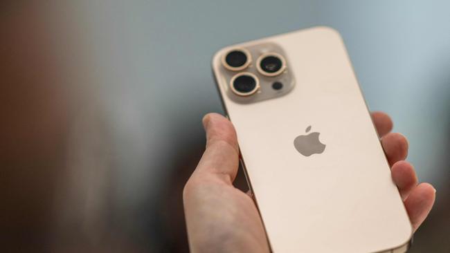 A person holds up a new iPhone 16 Pro (Photo by Nic COURY / AFP)