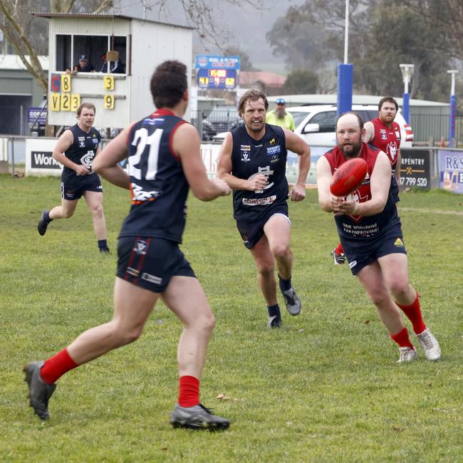 Evan Nicholas handpasses to Mitch Lauritzen with Adam Prior in pursuit. Picture: Corryong Courier