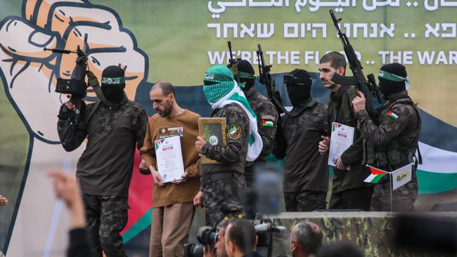 Palestinian Hamas fighters escort Israeli hostages.