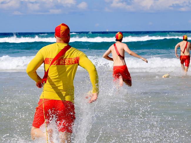 Main Beach Lifeguards charge through the surf thinking that people may have been caught in a rip but it turned out to be a false alarm. Pic Tim Marsden