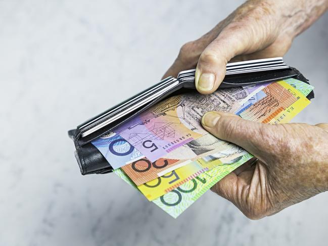 Payment. Close-up, senior female hands taking Australian banknotes (cash, currency) from purse containing many credit cards.  Horizontal, studio, copy space, spread notes.