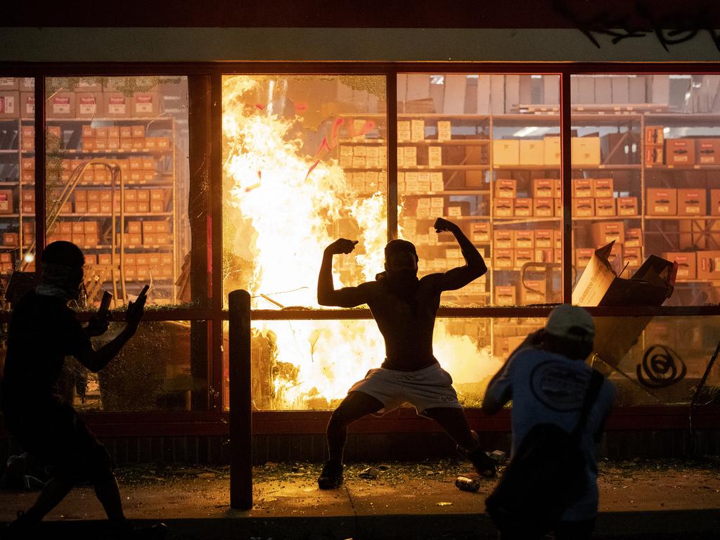 A man poses for a picture outside a burning store. Picture: Carlos Gonzalez/Star Tribune/AP