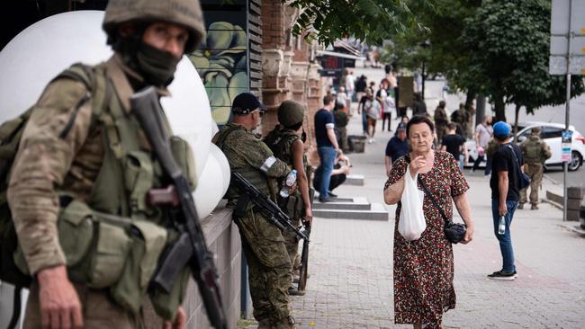 A local resident walks past members of Wagner group in Rostov-on-Don.