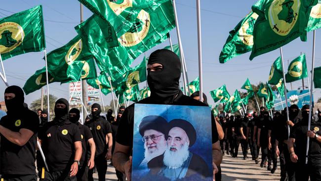 A member of the Imam Ali Battalions holds up a picture depicting Iran's late and current supreme leaders Ayatollah Ruhollah Khomeini, right, and Ali Khamenei, in Baghdad, Iraq, in early April. Picture: AFP