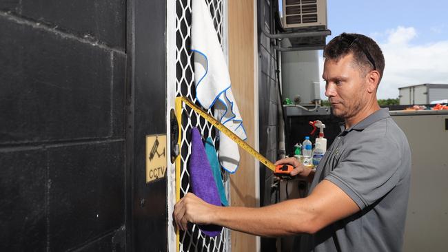 Network Car Rentals had six vehicles stolen in one night in May this year after youths broke through a window of the Westcourt business and stole the keys to the hire cars. Peter Ryan of Capital Glass and Aluminium measures up a new glass panel to fix the damage caused by the juveniles. Picture: Brendan Radke