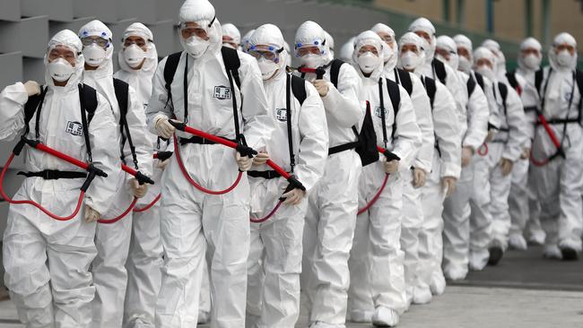 South Korean soldiers in protective gear move to spray disinfectant as part of preventive measures against the spread of COVID-19 at Dongdaegu railway station in Daegu Picture: AFP