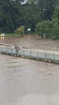 Boy casually pops a wheelie over flooding bridge 