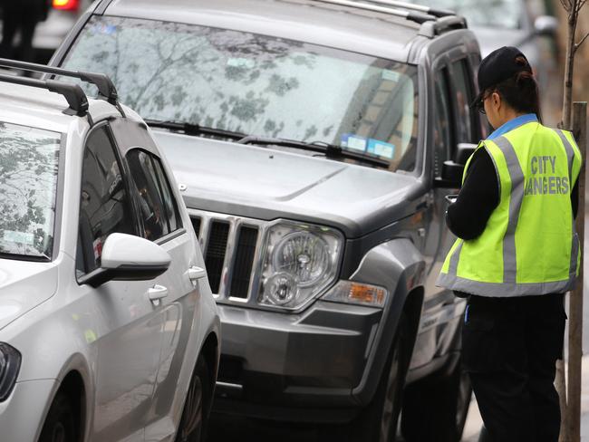 A City of Sydney parking inspector books a car on Cooper St, Surry Hills. Picture: John Grainger