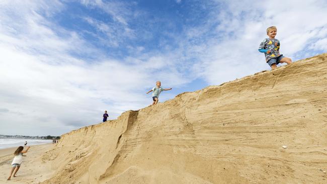 Kids play in the cliffs of erosion forming at Maroochydore as Cyclone Alfred continues to approach the coast. Picture Lachie Millard